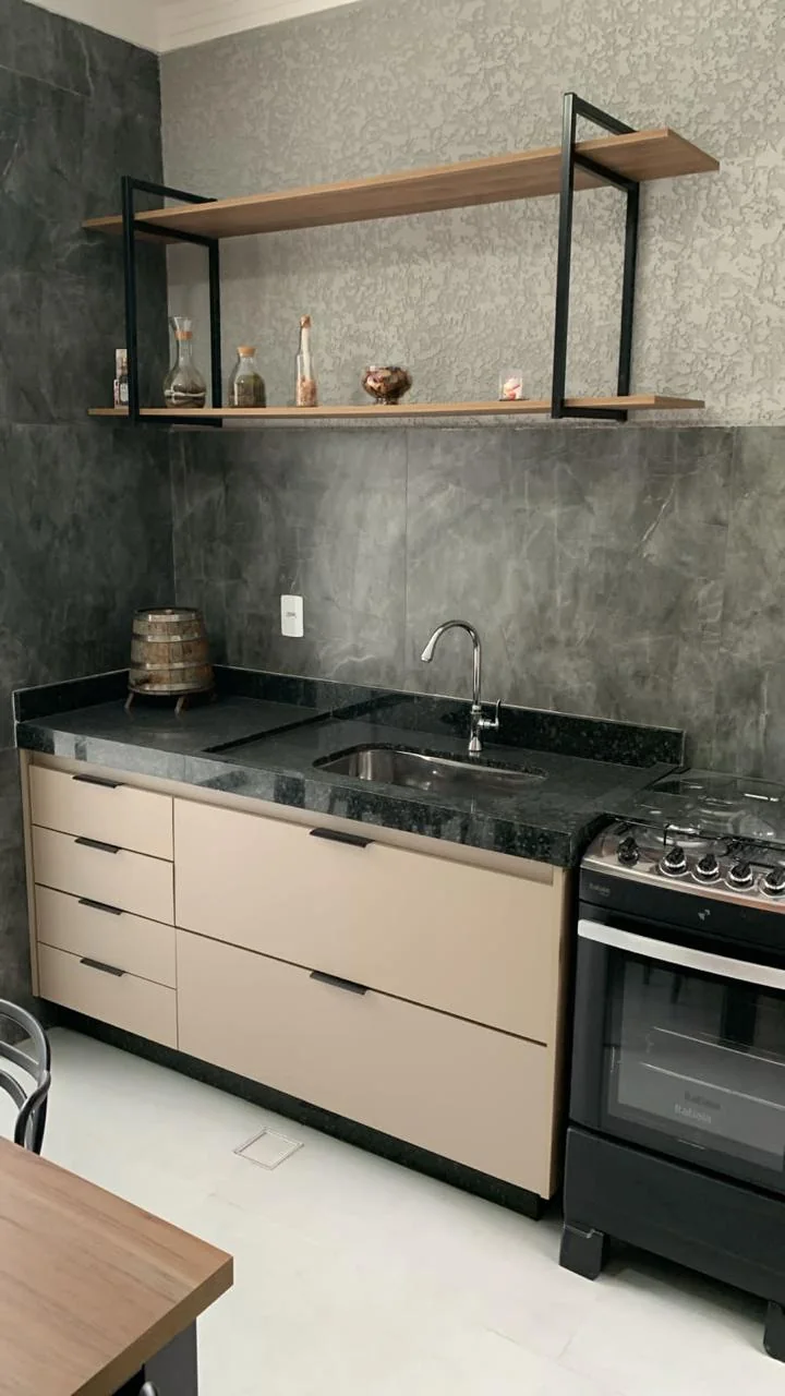 Cozinha planejada com bancada escura e prateleiras